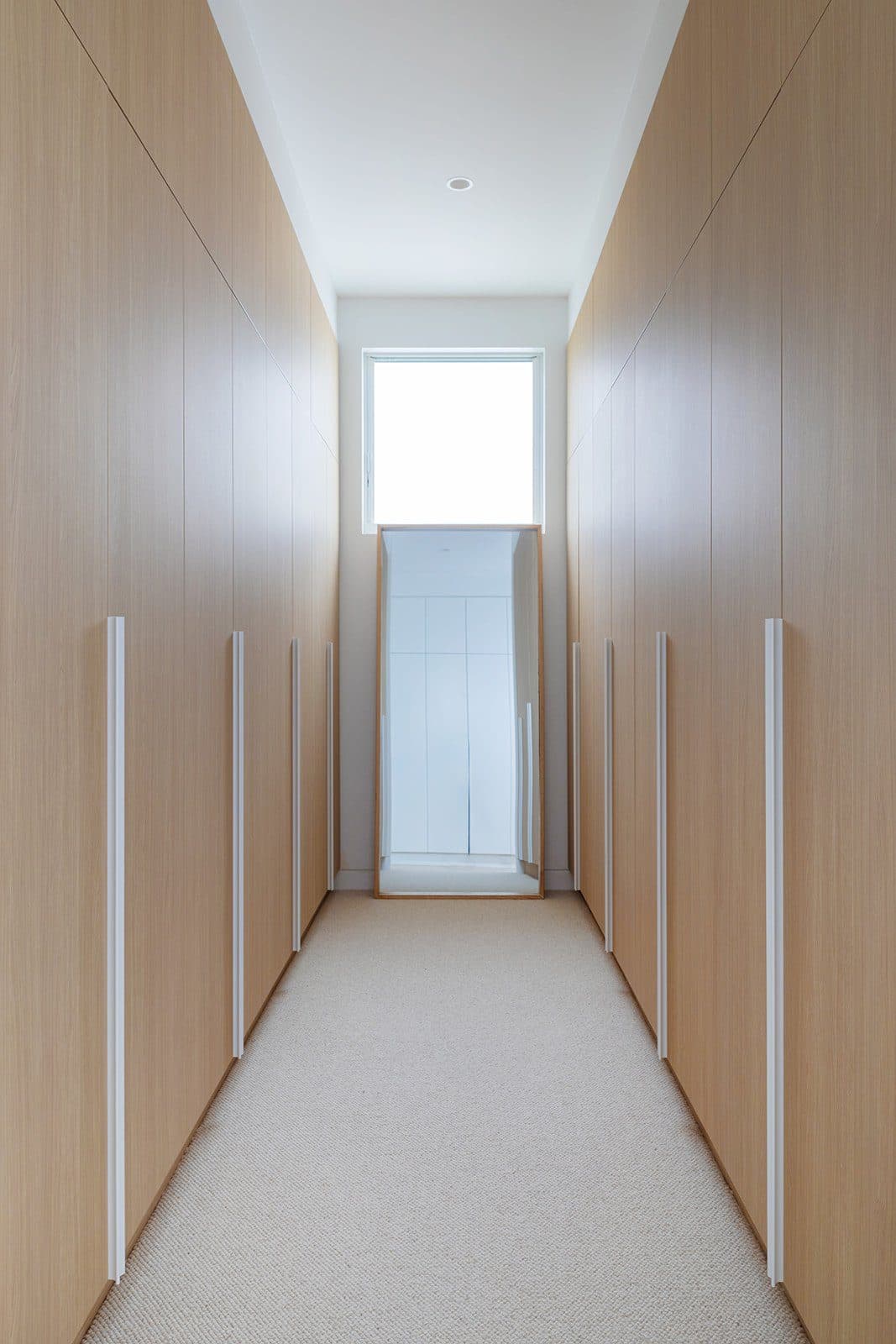 Robe corridor in oak joinery leading to a picture window