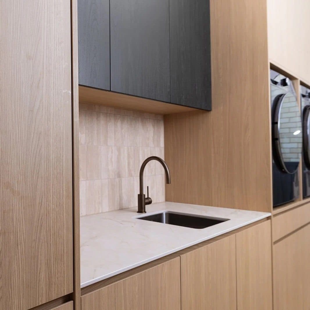 Laundry in oak joinery with stone benchtop and bronze tapware