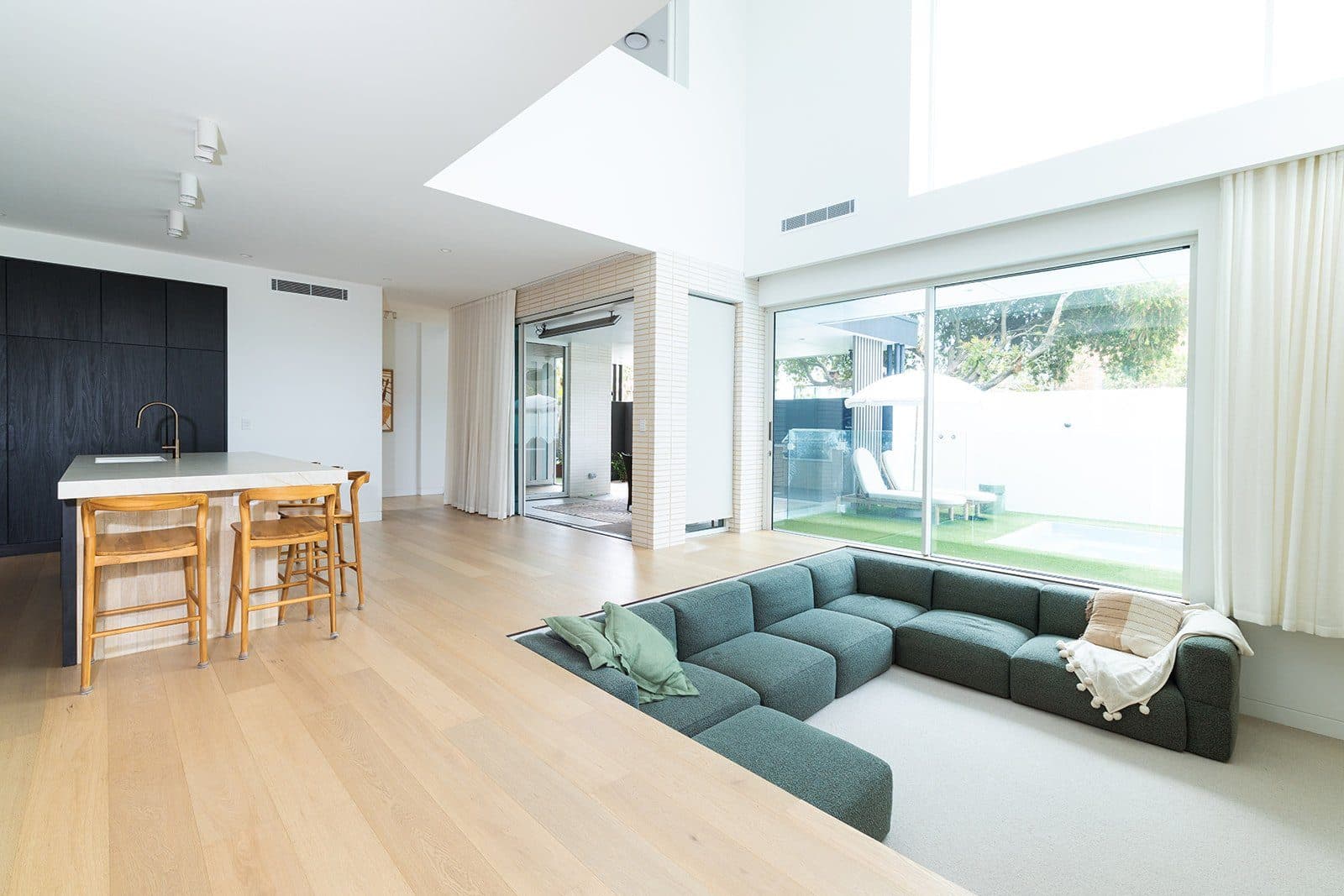 Living room with sunken green lounge and pale oak floors