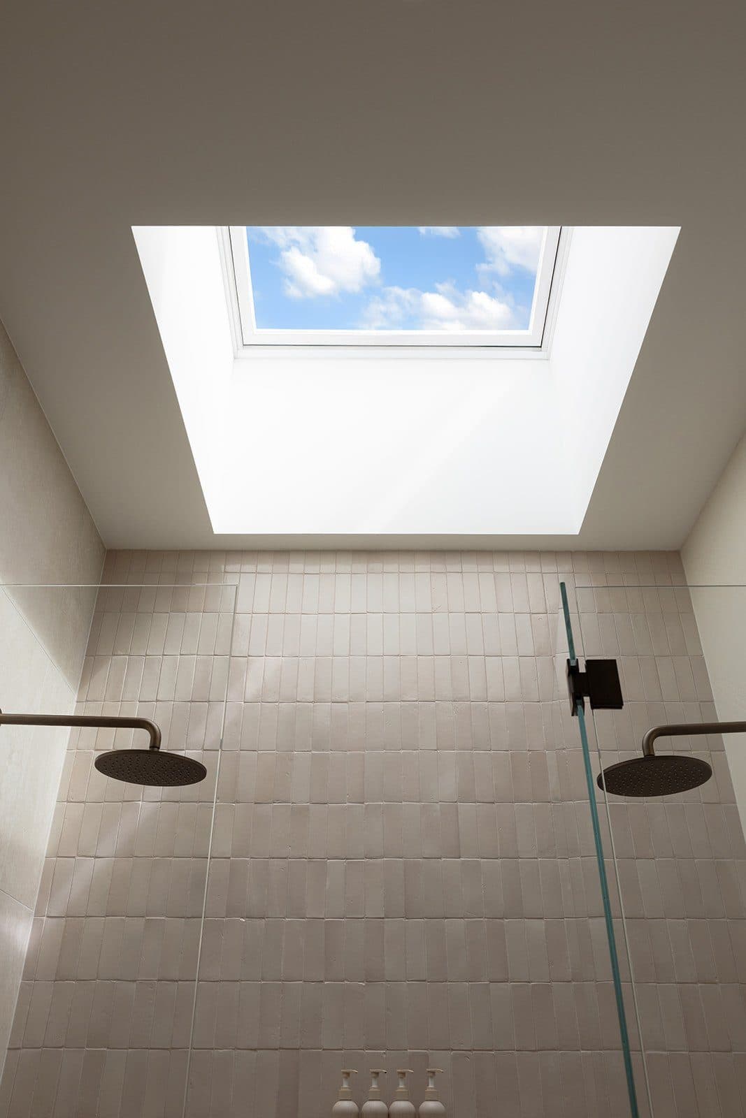Shower in tumbled stone tile lit by a full skylight