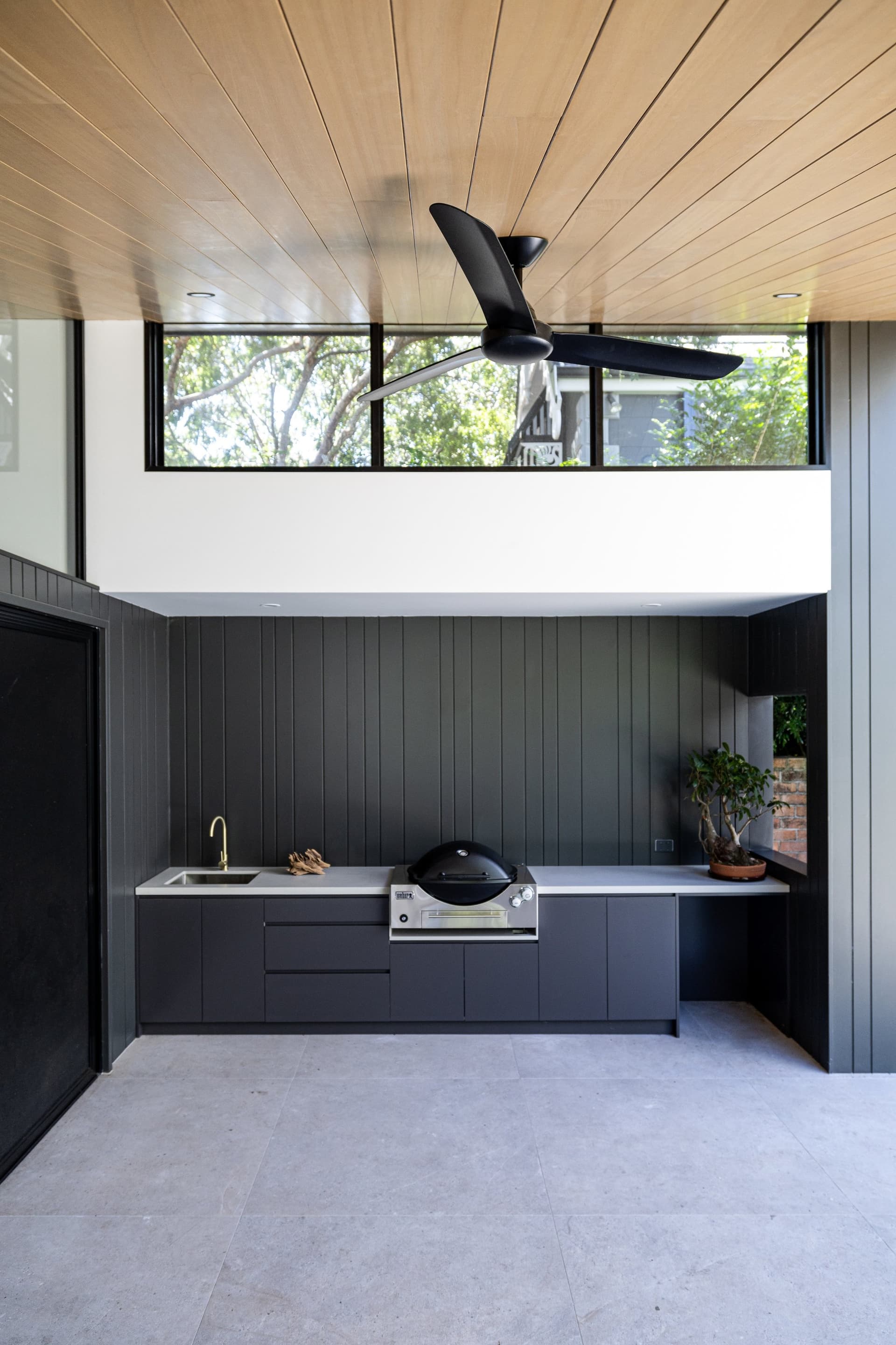 Outdoor kitchen under a timber-lined roof behind the cottage