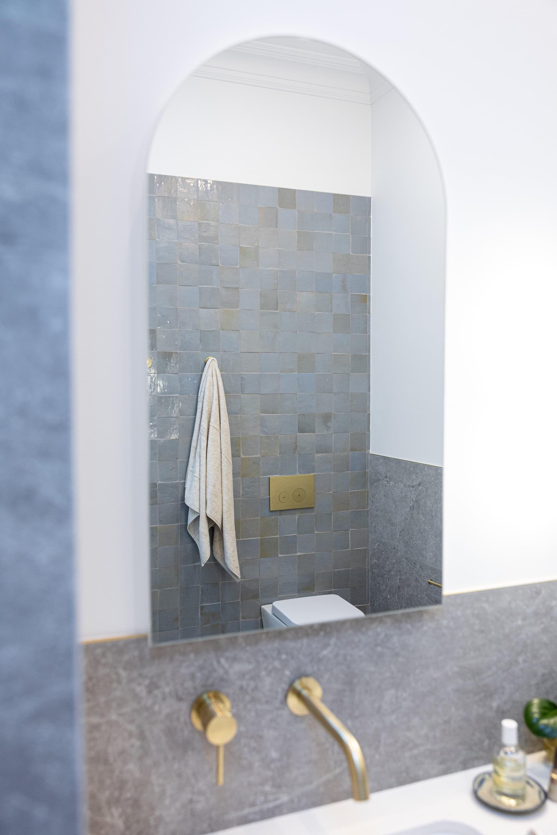 Arched shower niche in sea-green tile with brass tapware