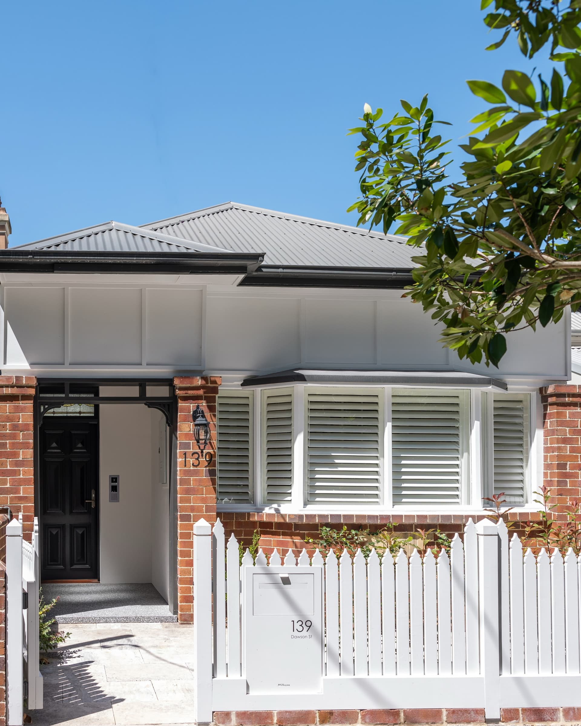 The restored heritage cottage front — brick, weatherboard and picket fence