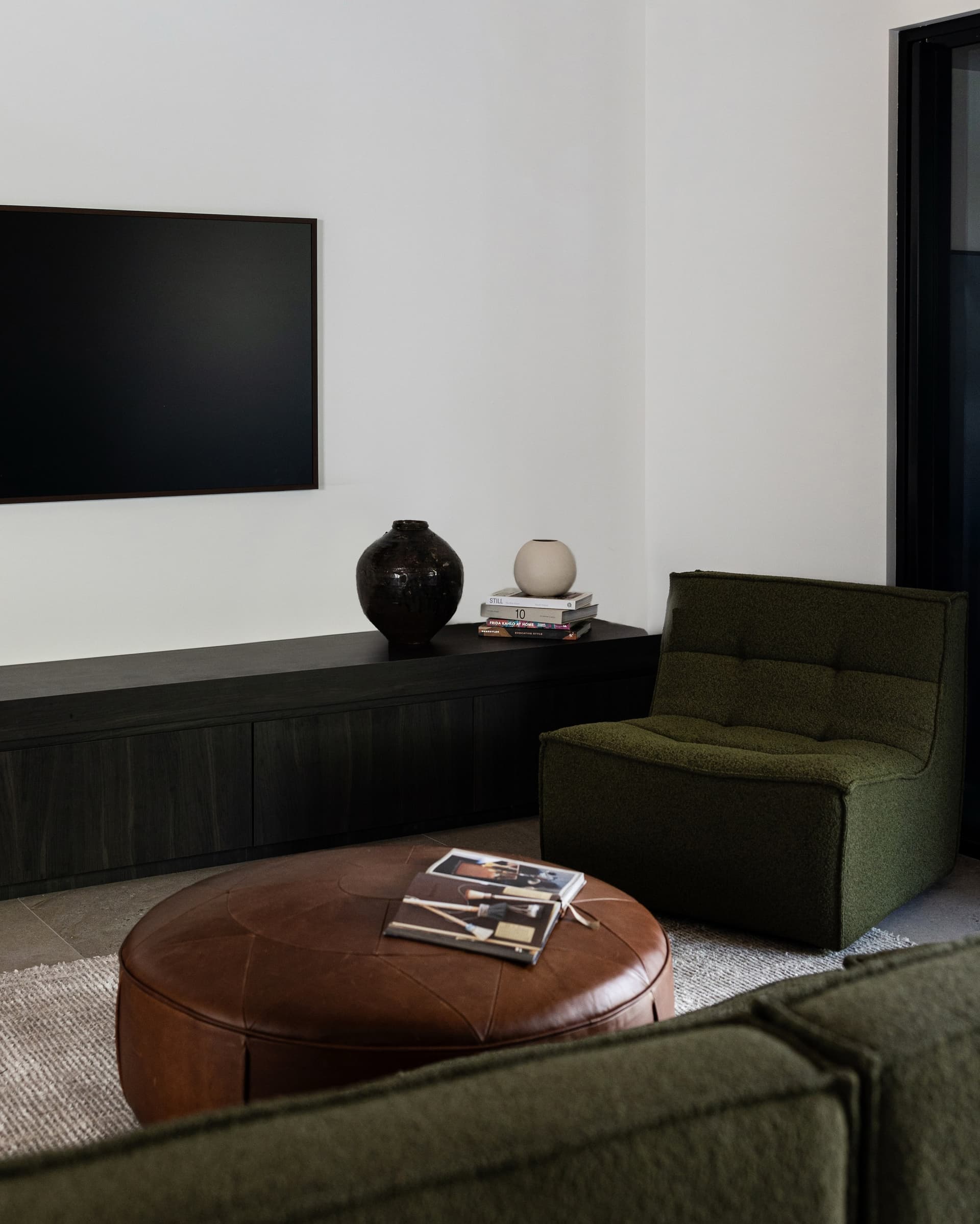 Living room — olive lounge, leather ottoman and black joinery