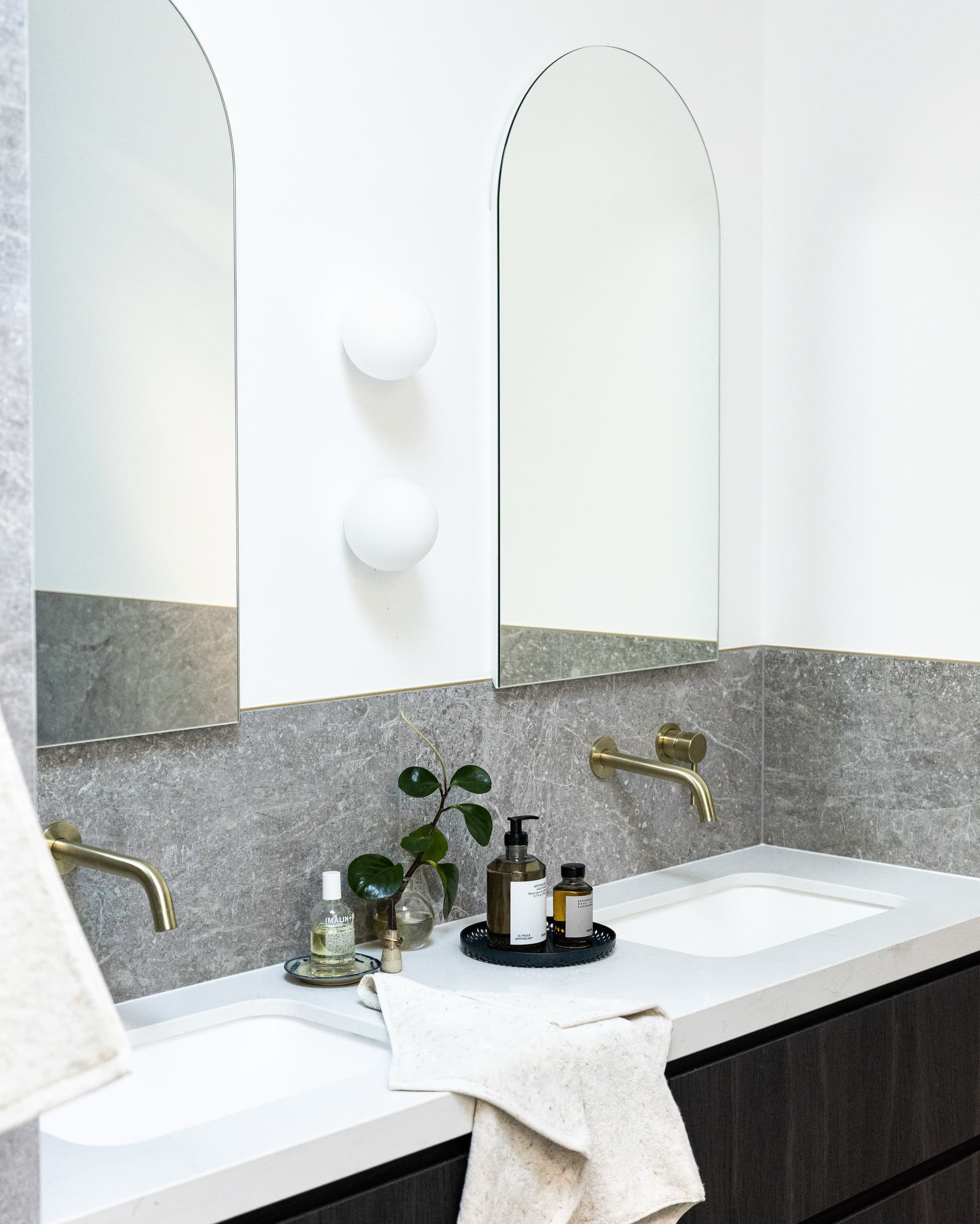 Terrazzo-topped vanity with arched mirror and brass taps