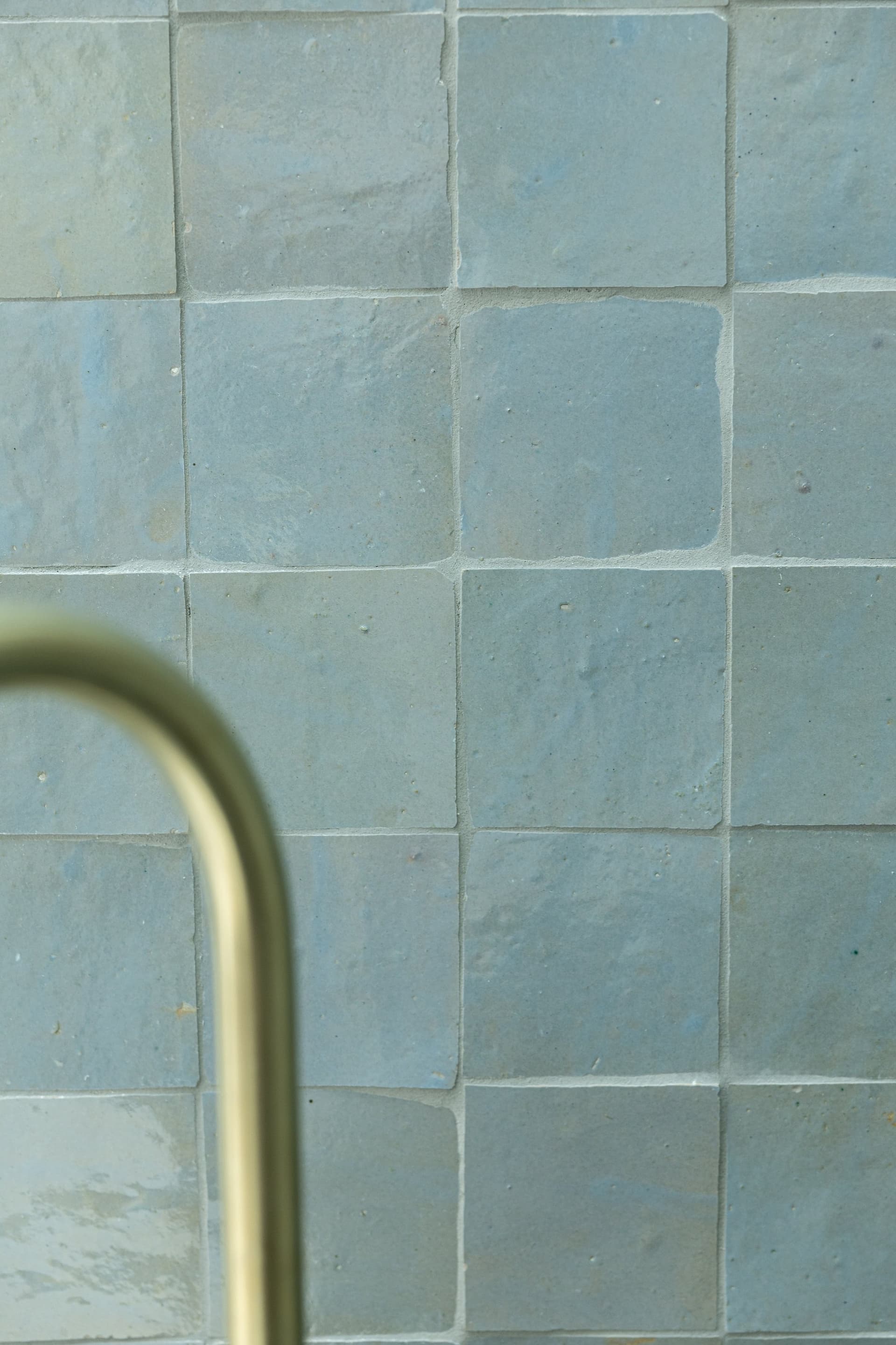 Sea-green zellige tiles with brass shower rail