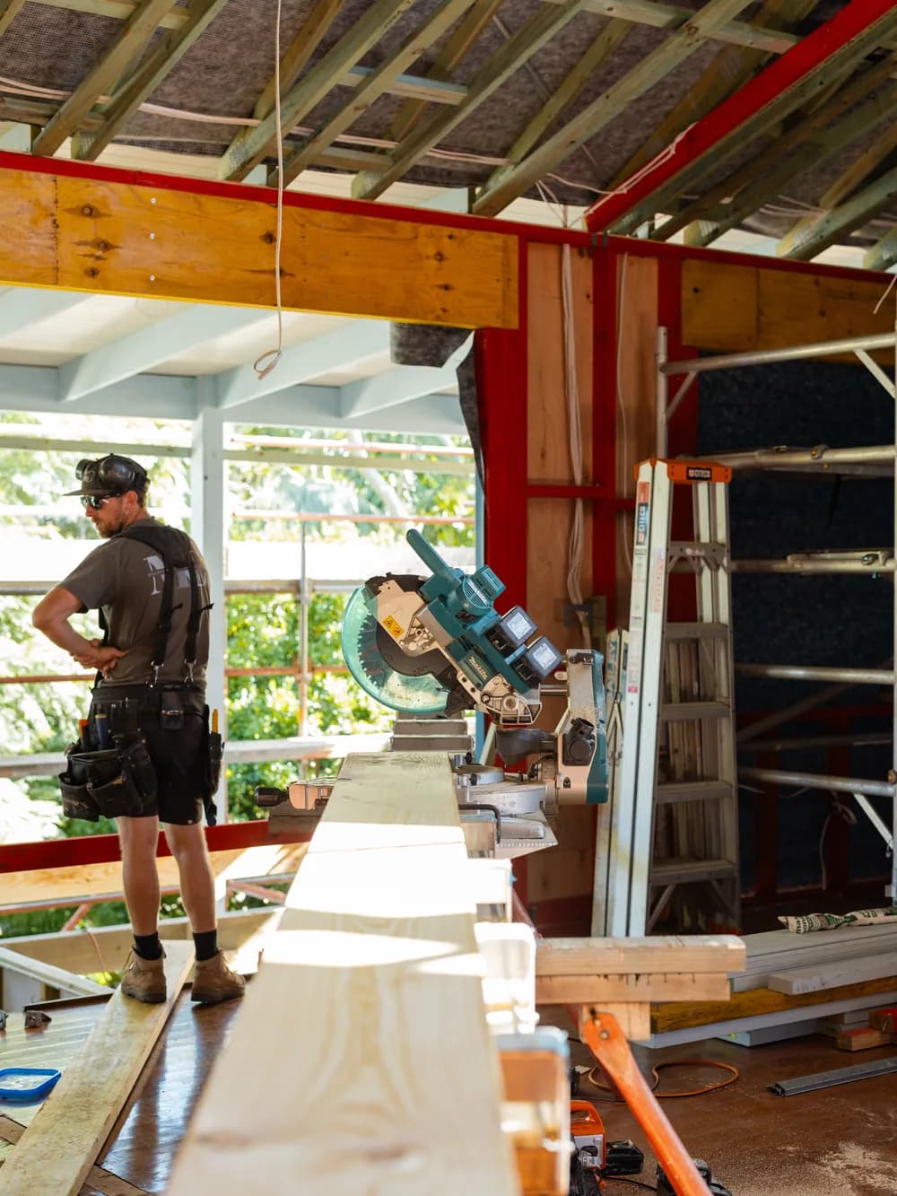 Michael on site at the drop saw, cutting timber during the framing stage