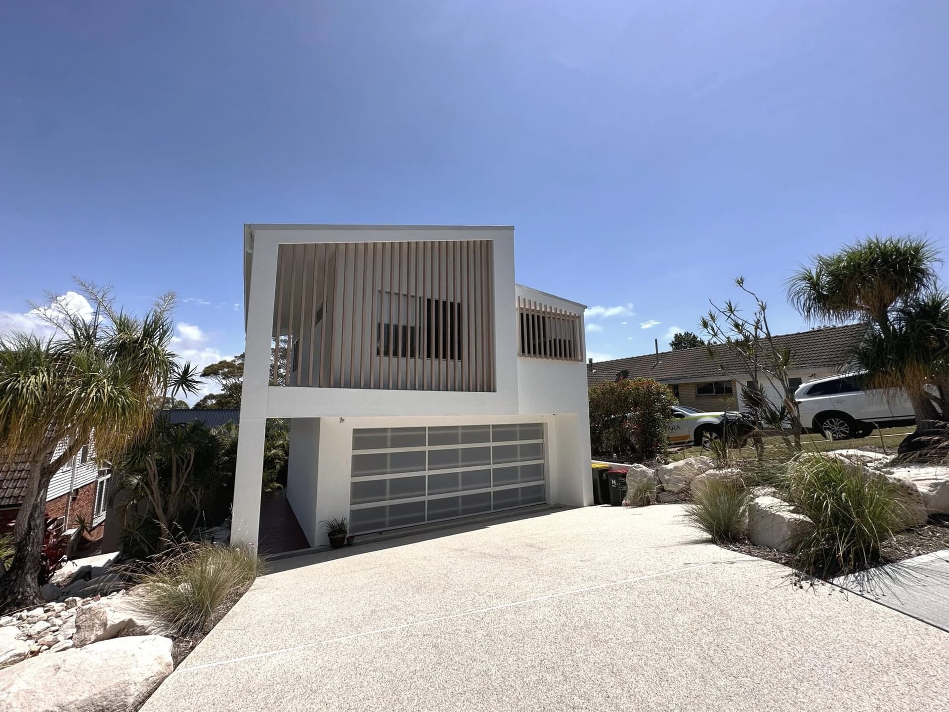 Rembrandt Drive from the street — white render, timber battens and charcoal fence