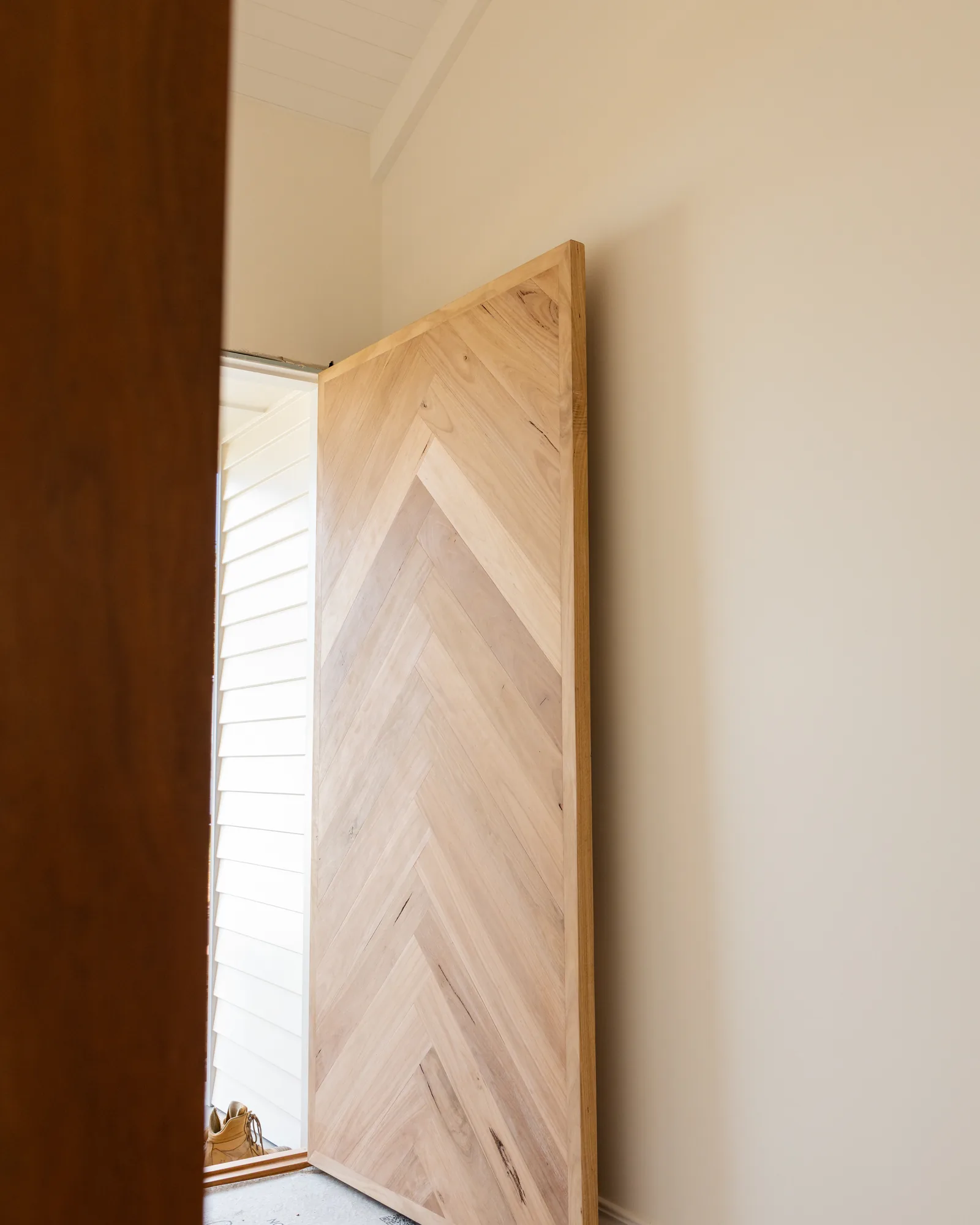 Tall timber door with chevron detail standing in a doorway
