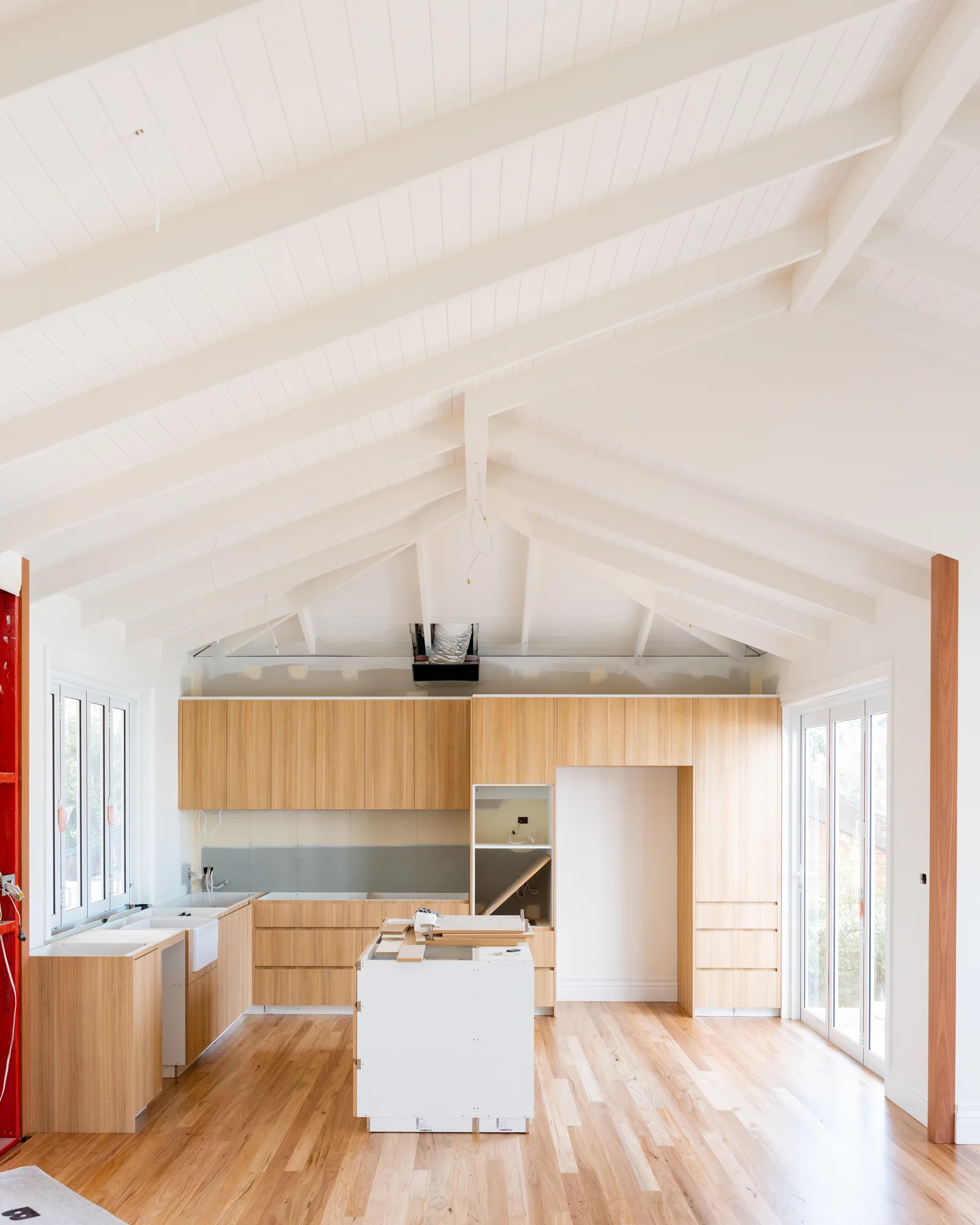 Finished Dudley kitchen under a raked ceiling with exposed white beams and oak joinery
