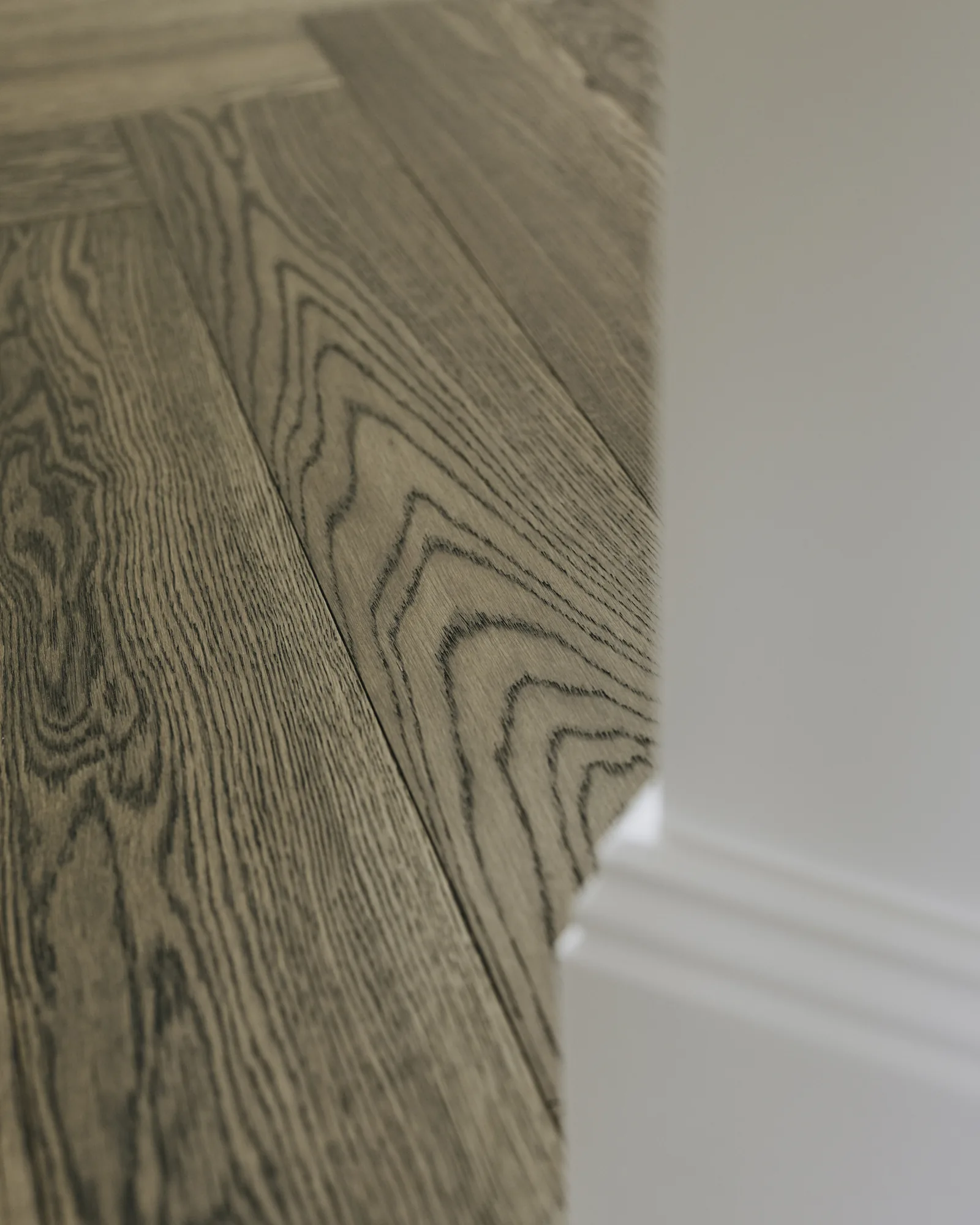 Herringbone oak flooring meeting a deep skirting board